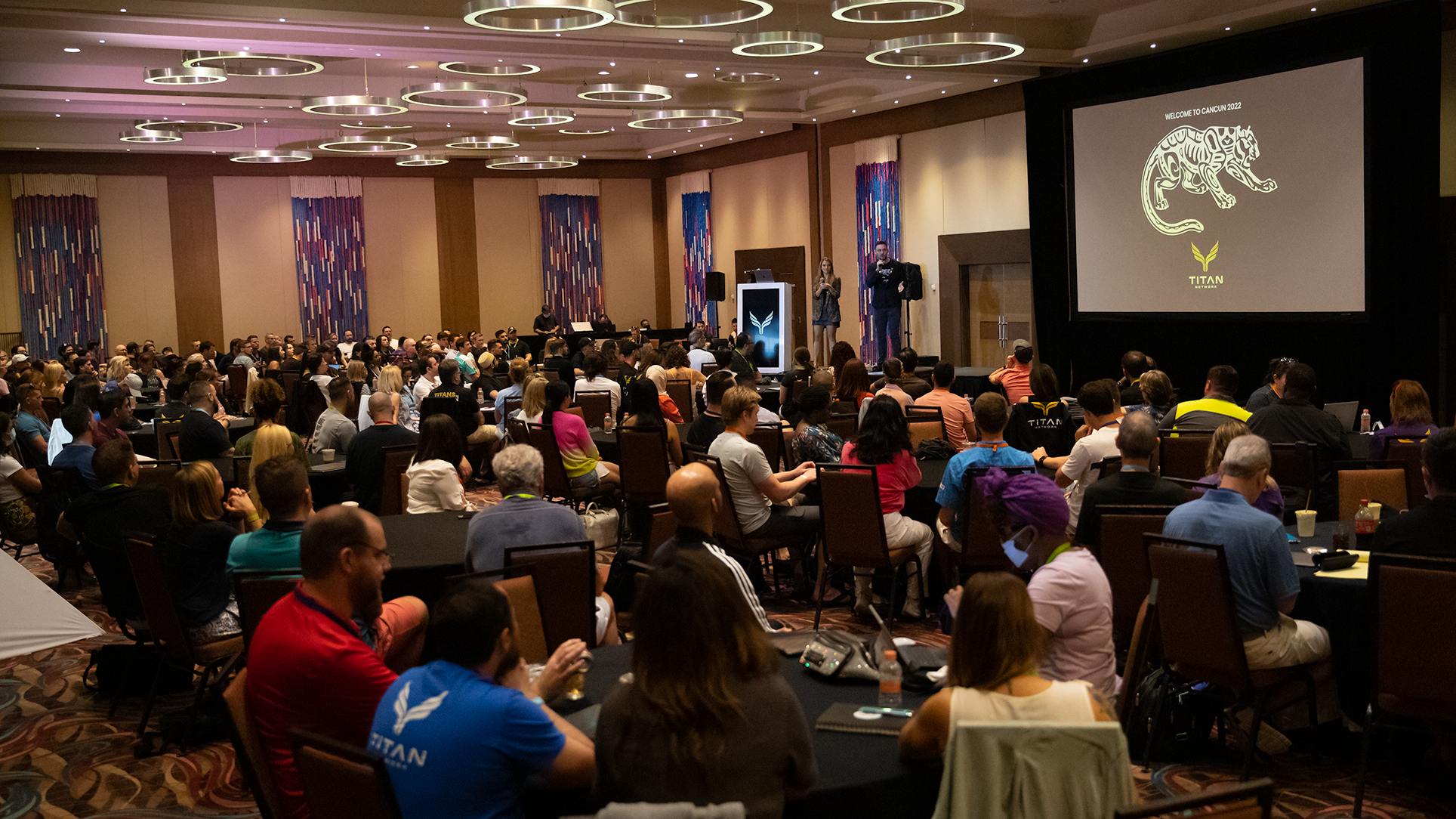 Dan speaking confidently on stage at a Masterminds & Community event, engaging a captivated audience.